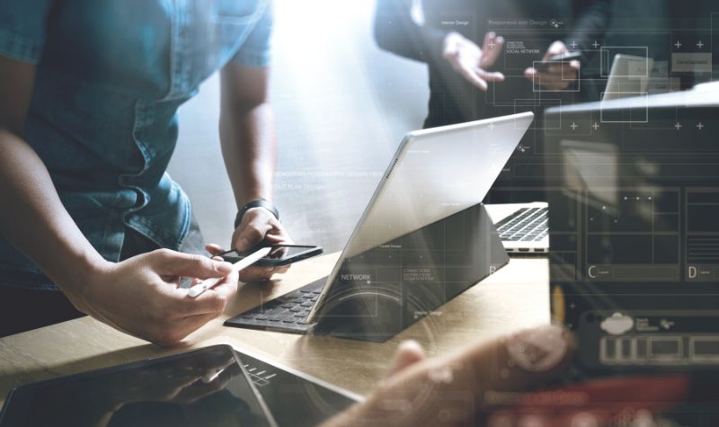 coworkers collaborating on several digital devices